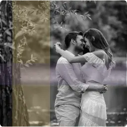 Engaged couple embracing beside wooded lake