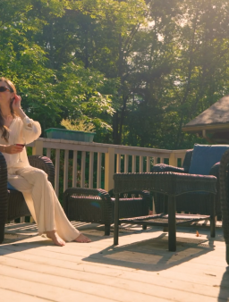 Woman relaxing on wicker chairs on tree-lined deck